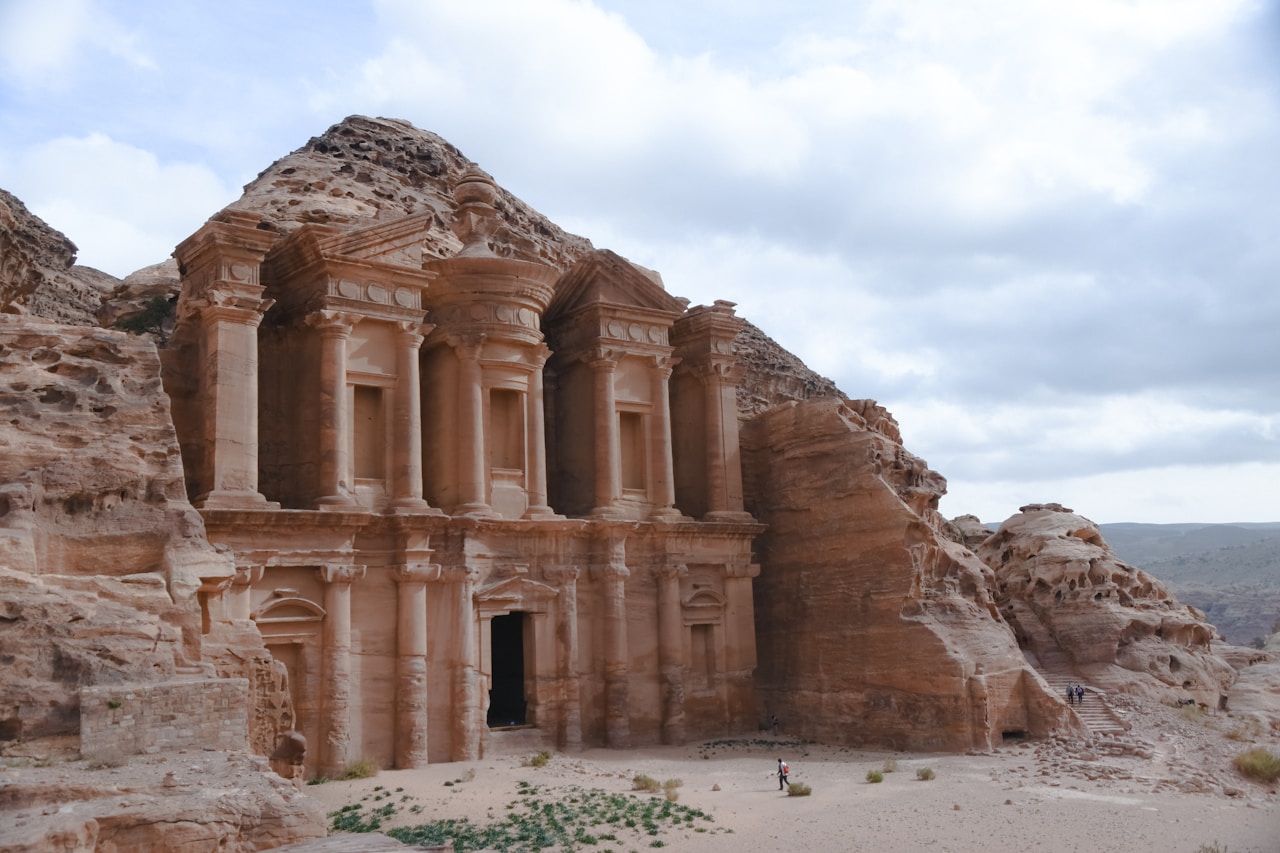 Petra archaeological site with carved structures and visitors on a wide plaza