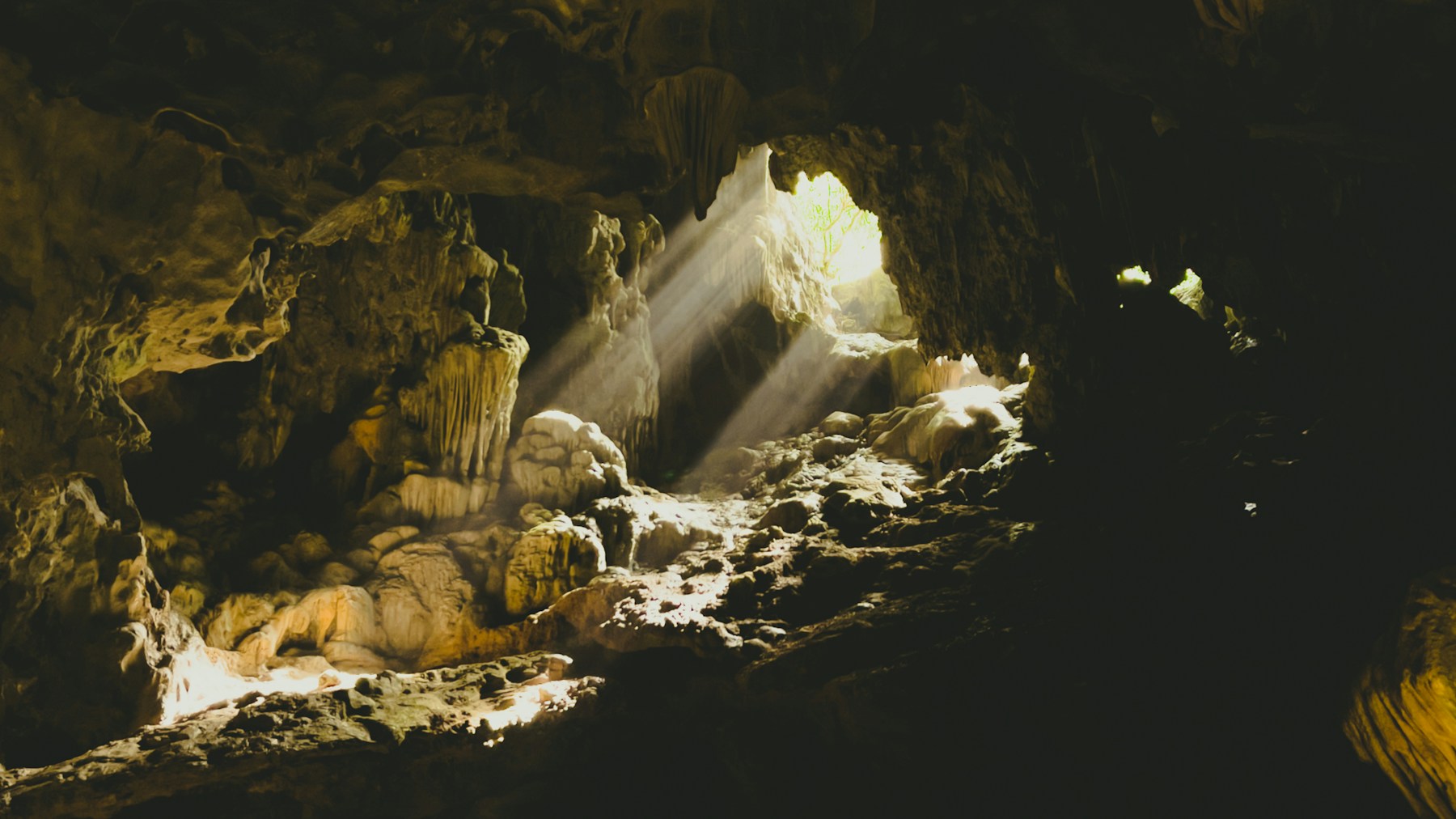 Limestone cave interior with sunbeams through a ceiling opening