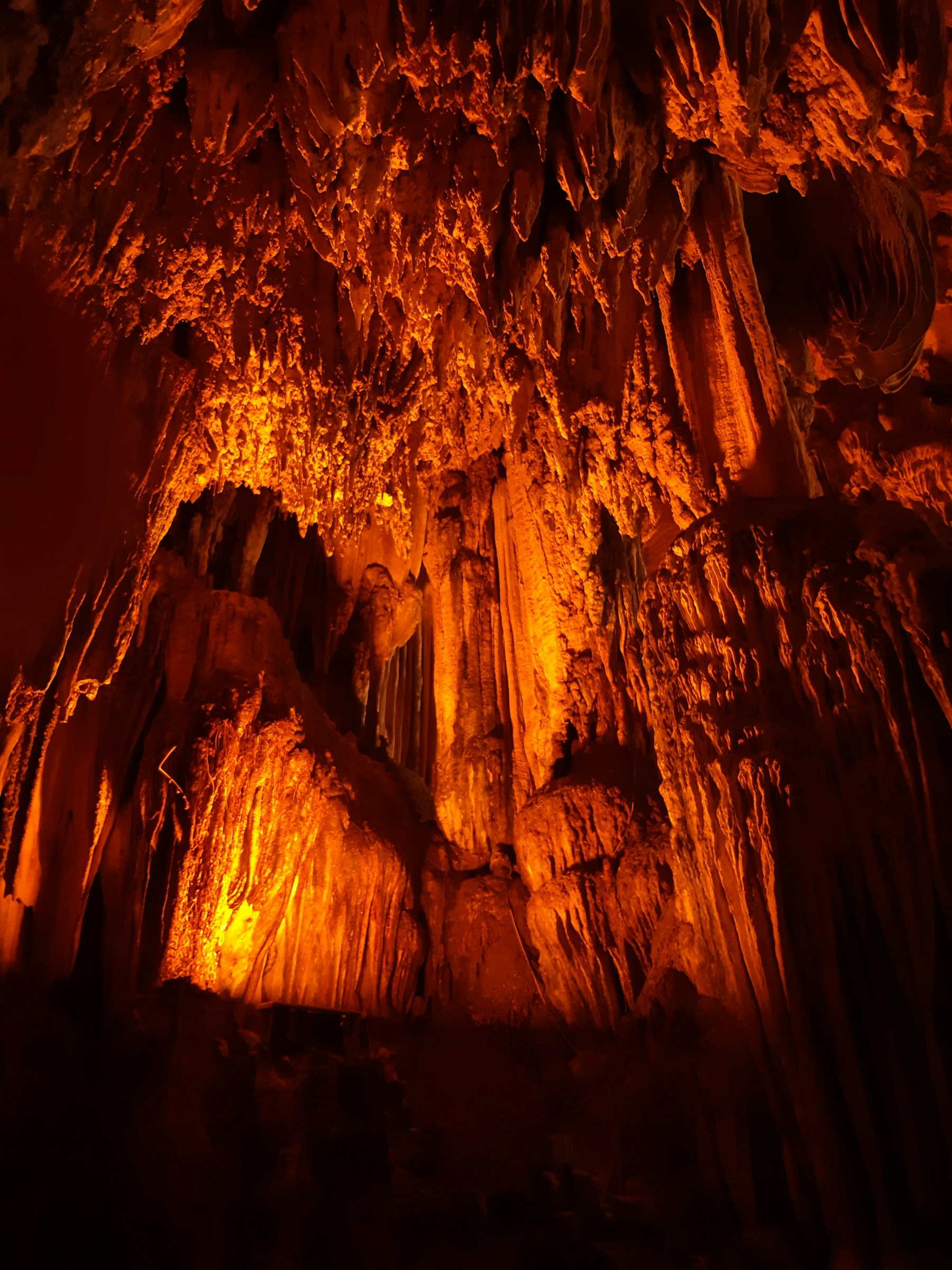 Stalactites and flowstone in a tall limestone cave chamber