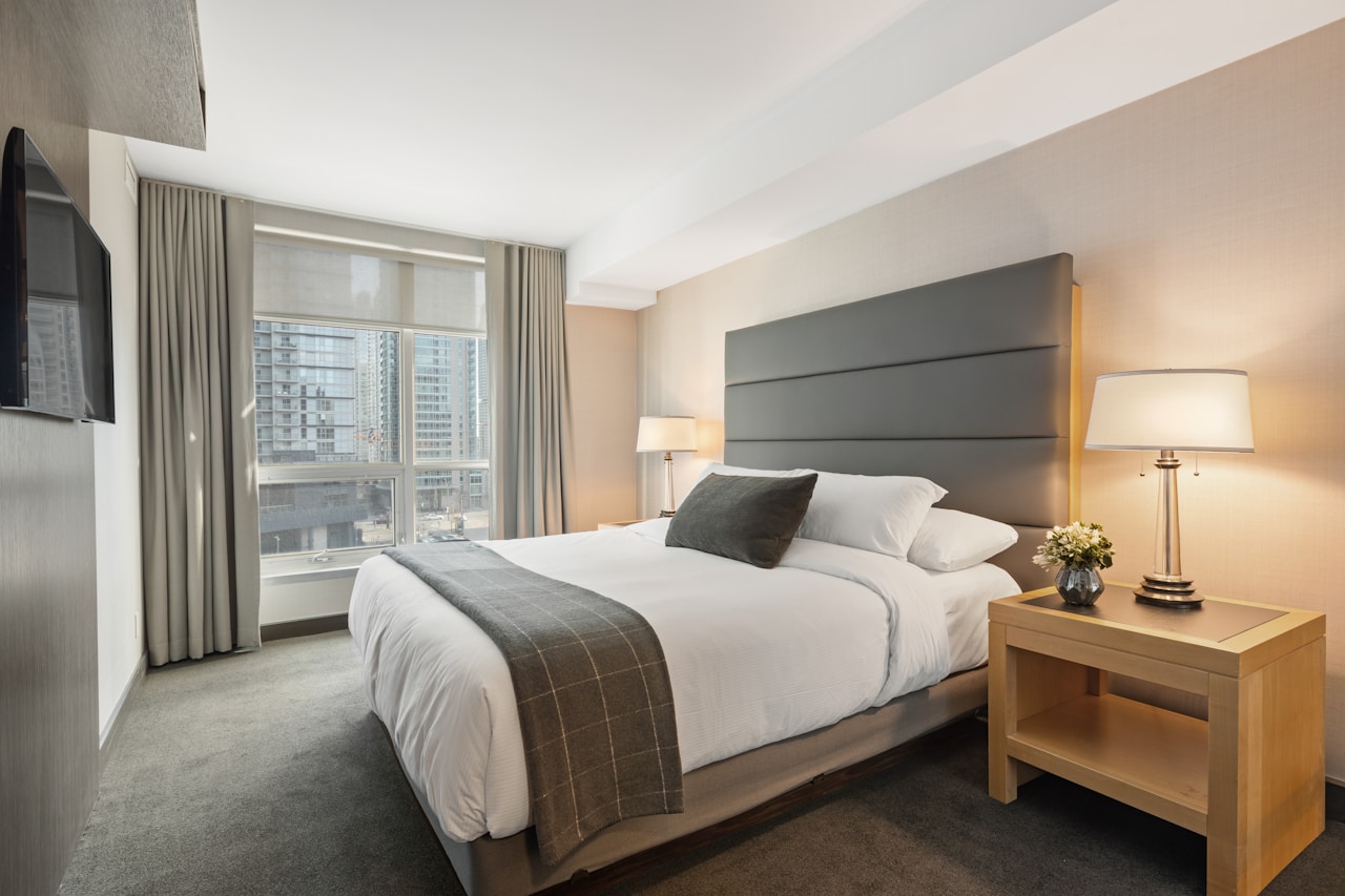 Modern hotel-style bedroom with crisp linens and soft bedside lighting