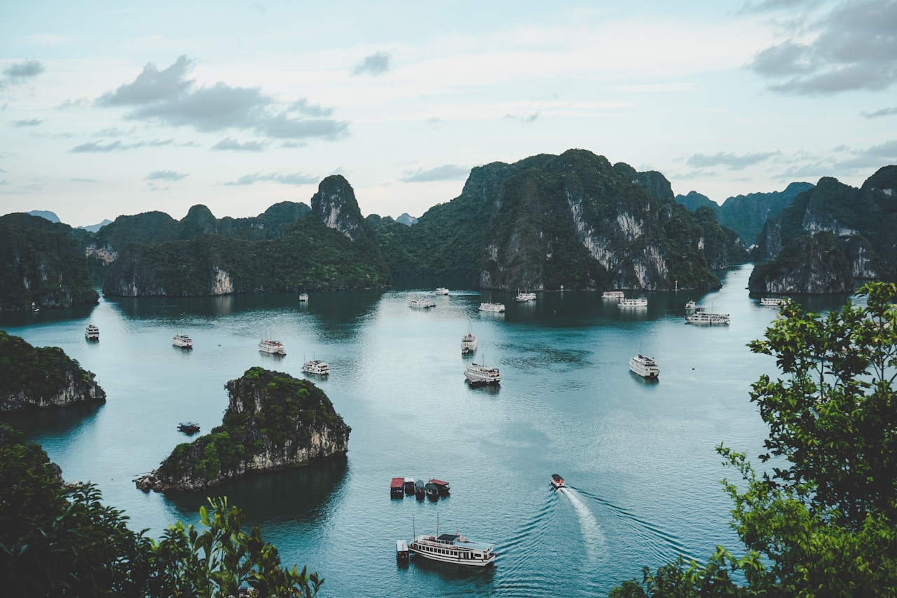 Limestone karst islands rising from calm teal water with tour boats